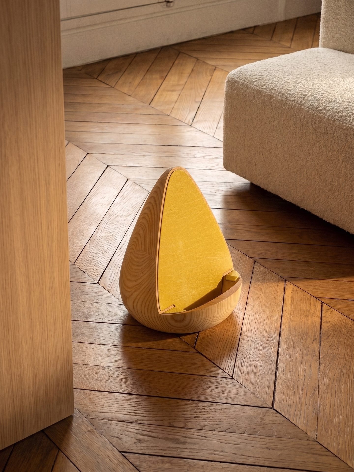 Stèle en bois clair garnie de jaune sur un parquet en point de Hongrie