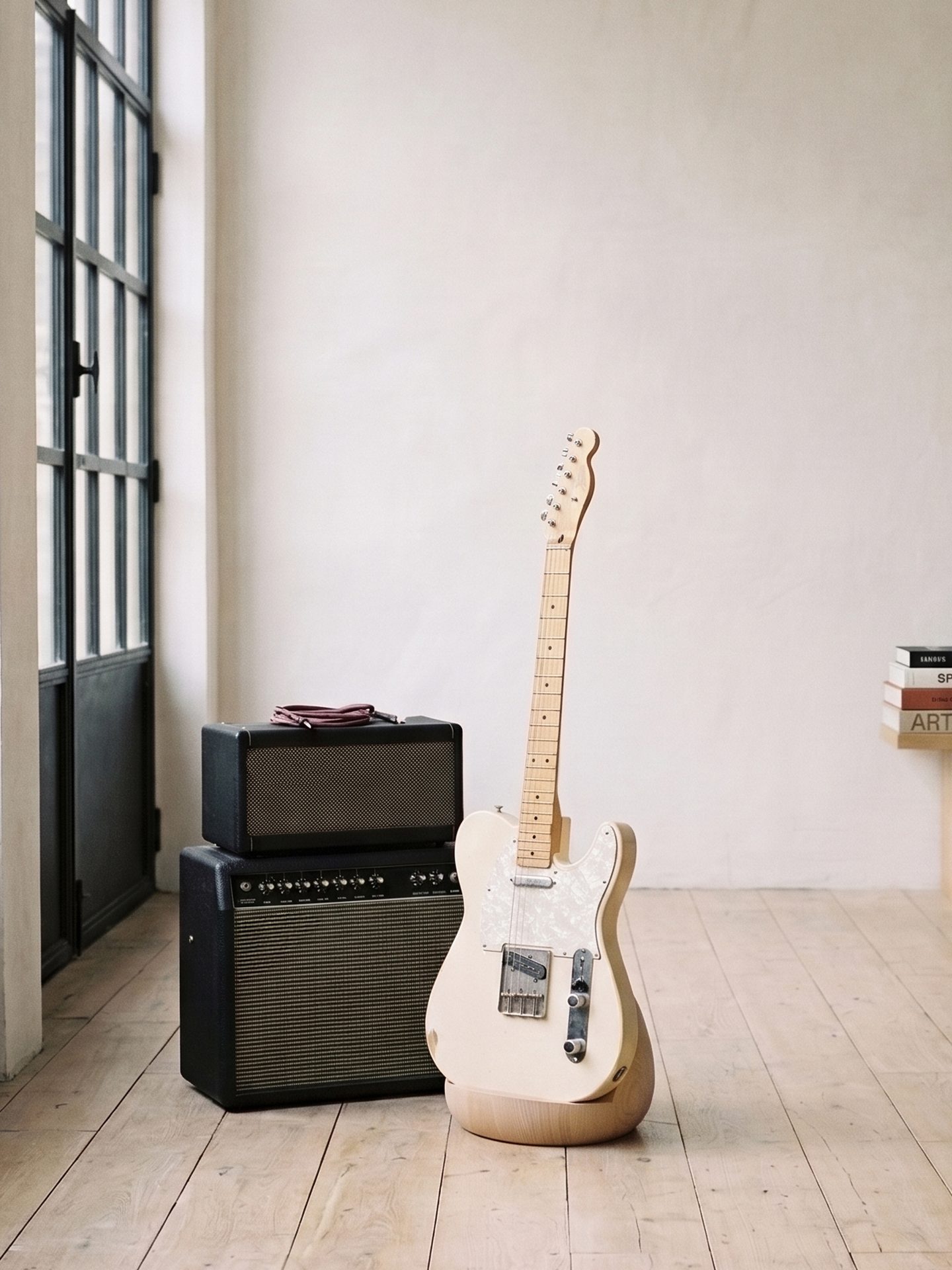 Telecaster crème sur la Stèle en bois clair, à côté d'un ampli